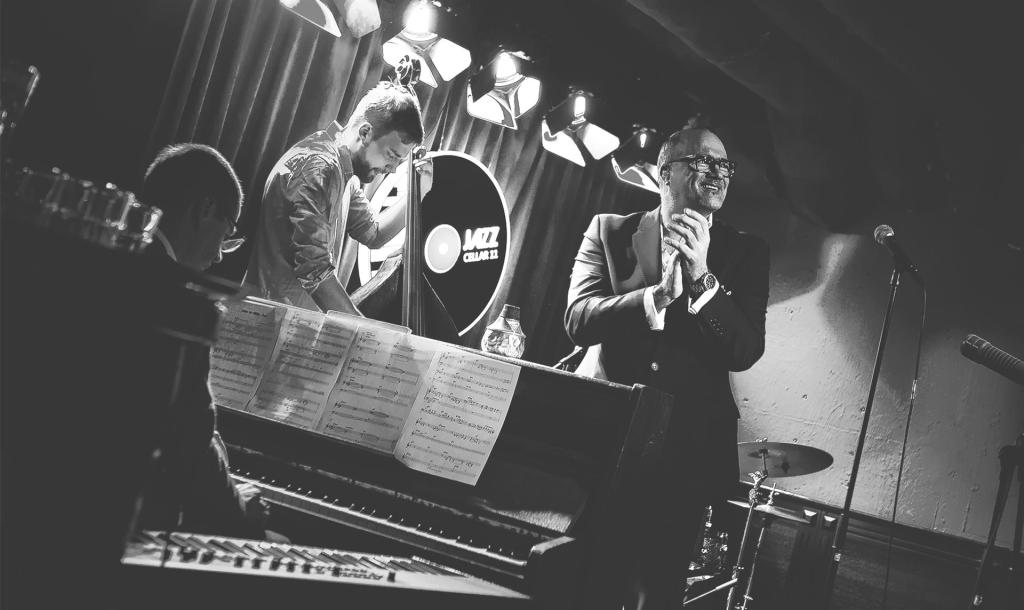 Schwarzweißbild von Sänger Jeff Cascaro mit Pianist und Kontrabassist
